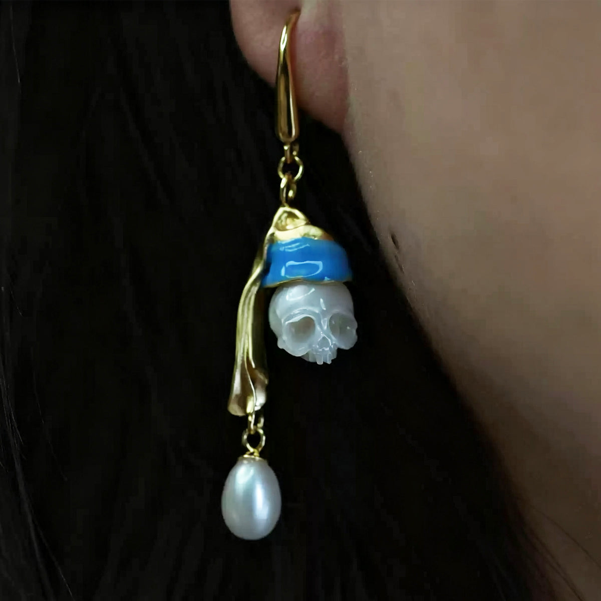 Hand-carved figure of a girl wearing pearl skull earrings